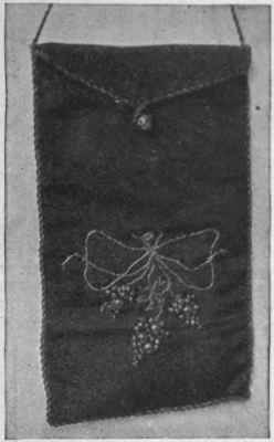 Flat Bridge Purse. This can also be used for a small glove handkerchief, folded flat. From its shape it can be tucked into the belt or the pocket of a muff or fur coat. It measures four inches. Gold thread fashions the bow on the green silk beloved of Napoleon. Gold beads of varying sizes make the grapes; the design reproduces a First Empire pattern.
