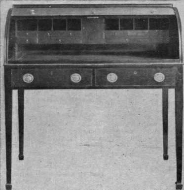 A table of the Carlton House design. This table possesses a tambour top. It also has a sliding writing flap, which pulls out when the top is pushed up