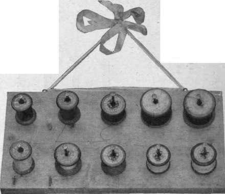 A wooden panel fitted with wire nails, for holding the various reels of cotton