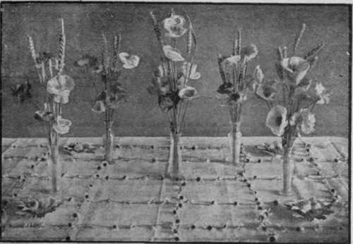 A decoration for harvest time, consisting of wild or Shirley poppies and wheat in slender vases, placed upon squares formed of daisy heads