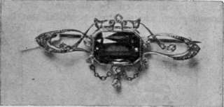 A green tourmaline and small diamonds. Tourmalines combine well with other stones and are much used in artistic ornaments