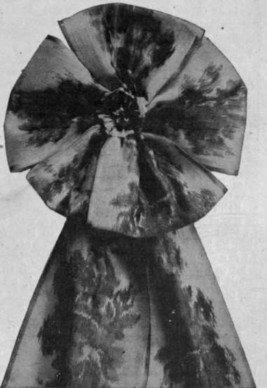 A sash of Chine ribbon arranged with a rosette of loops is a charming adjunct to a young girl's costume