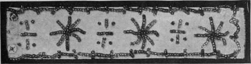 A white velvet wristband with a design of stars and quaint crosses in beads. Such bands form a pretty finish if worn with three quarter length sleeves
