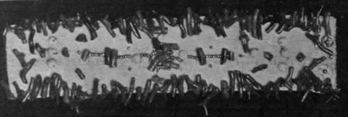 Deep red coral is effectively displayed on a white velvet bracelet, sewn on in an irregular design, interspersed with small steel beads and a few ivory beads in a larger size