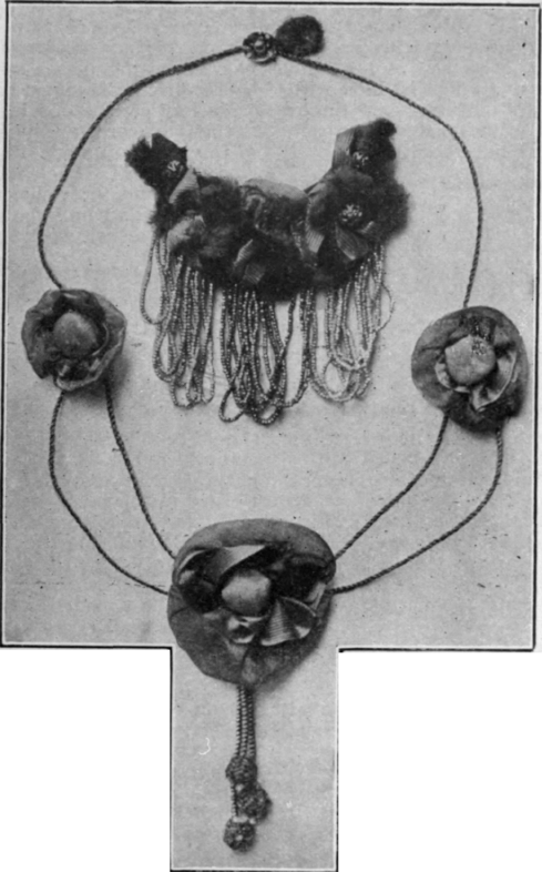 An original floral necklet of gold cord and roses for wearing with a lace or silk blouse. Inside the necklet is shown a crescent shaped brooch with a fringe of tiny metal beads the knot of rose stalks which is added, and rose stems are placed here and there amongst the flowers